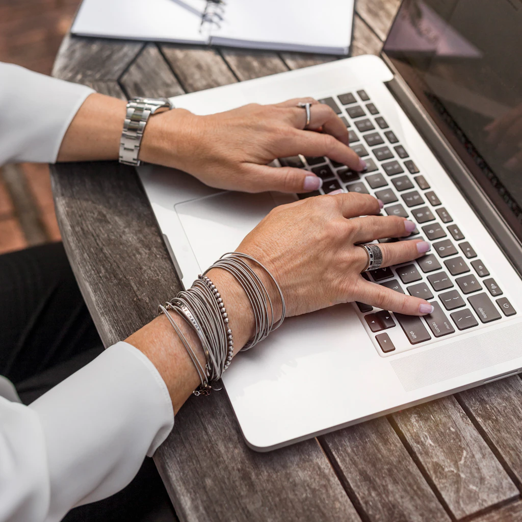 Hands typing on a laptop on a wooden table